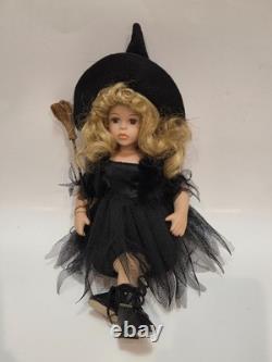 Vintage porcelain witch doll featuring blonde curly hair, a black witch hat