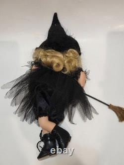 Vintage porcelain witch doll featuring blonde curly hair, a black witch hat