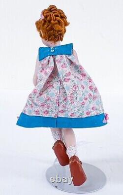 Jeune fille vintage avec robe courte fleurie, cheveux bouclés roux, poupée de porcelaine miniature