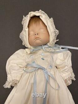 Poupée en porcelaine pour bébé VTG dans une robe de baptême blanche avec des finitions bleues et le visage endormi.