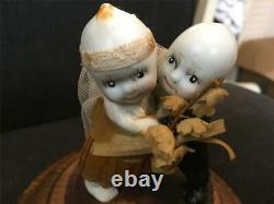 Poupées Kewpie de couple de mariage antiques sur un support dans une vitrine en verre et bois Rose O'Neill